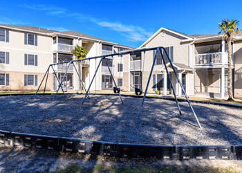 A playground with a swing set in front of apartment buildings